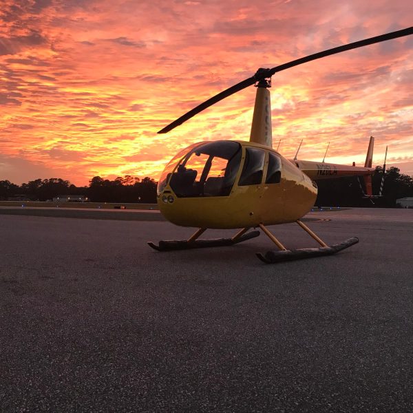 a small airplane sitting on the tarmac at sunset