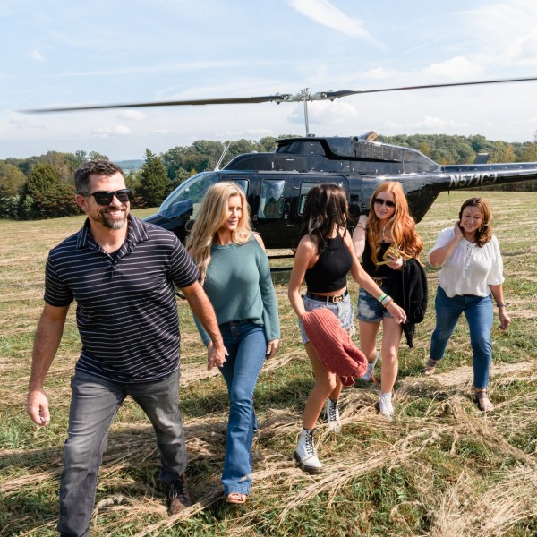 a group of people standing on top of a grass covered field