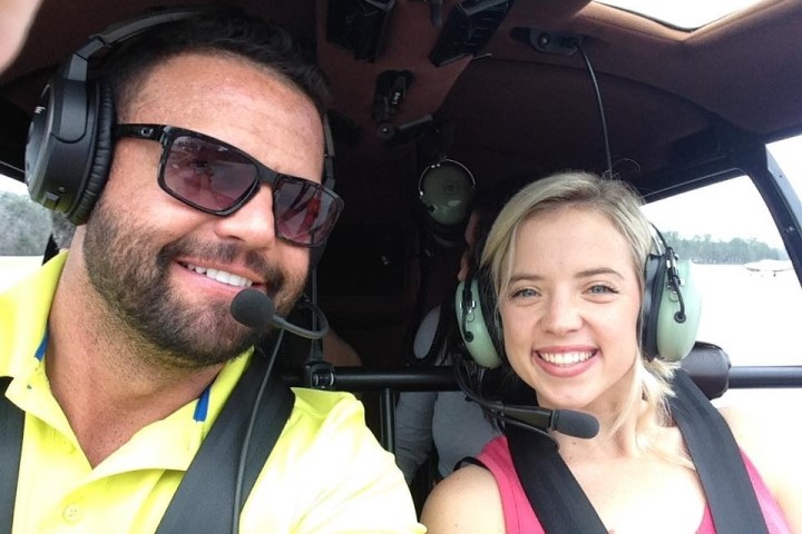 Two people wearing headsets in an aircraft cockpit, smiling for a selfie.
